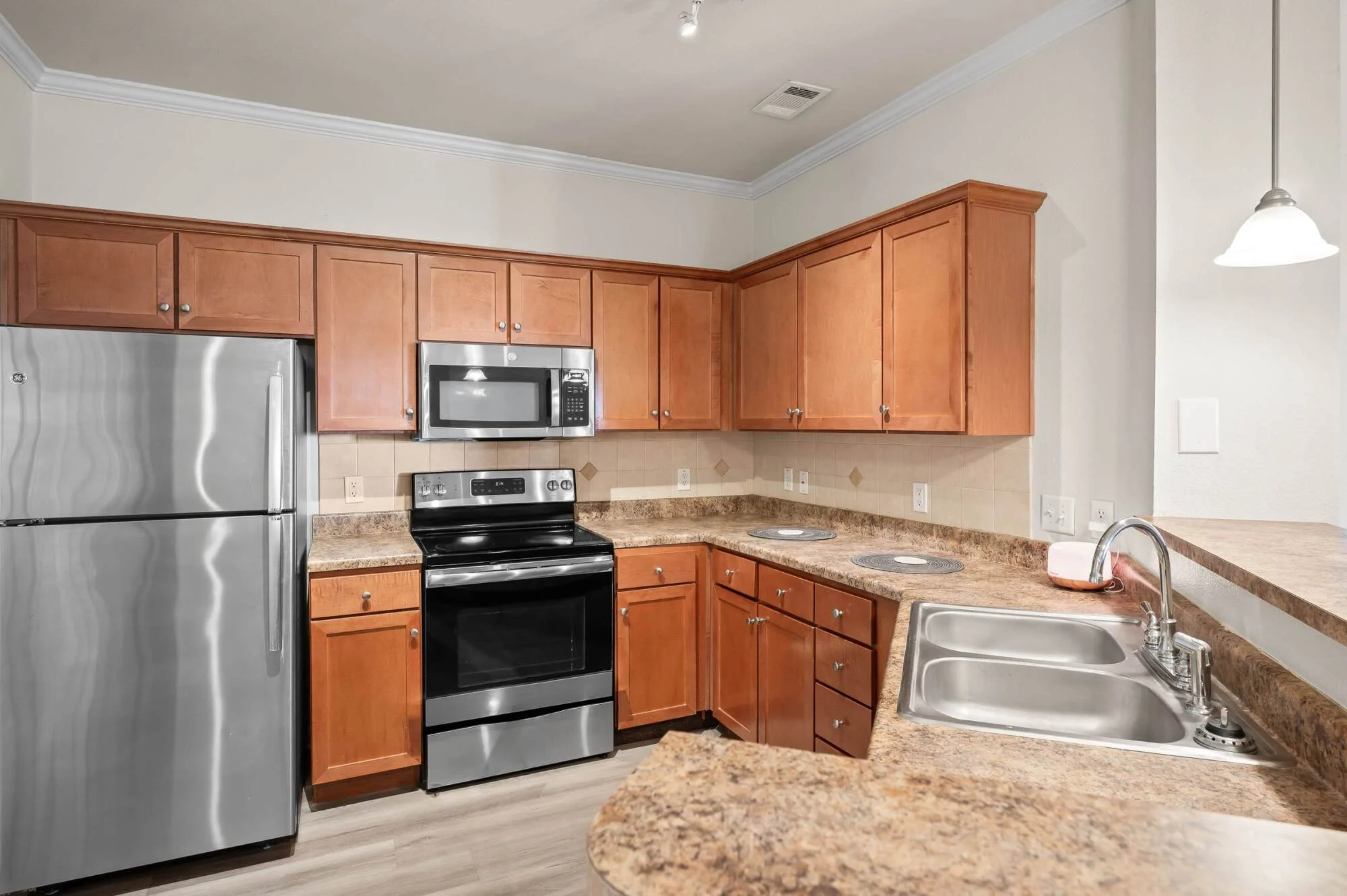 Modern kitchen with wood cabinets, stainless steel appliances, and marble-look countertops at Belterra apartments in Fort Worth, Texas